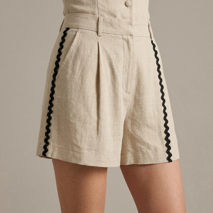 Model wearing beige-contrasting-button-shorts with close focus on the product