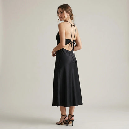 Second natural lifestyle image of a model wearing Black Halter Tie Satin Midi Dress